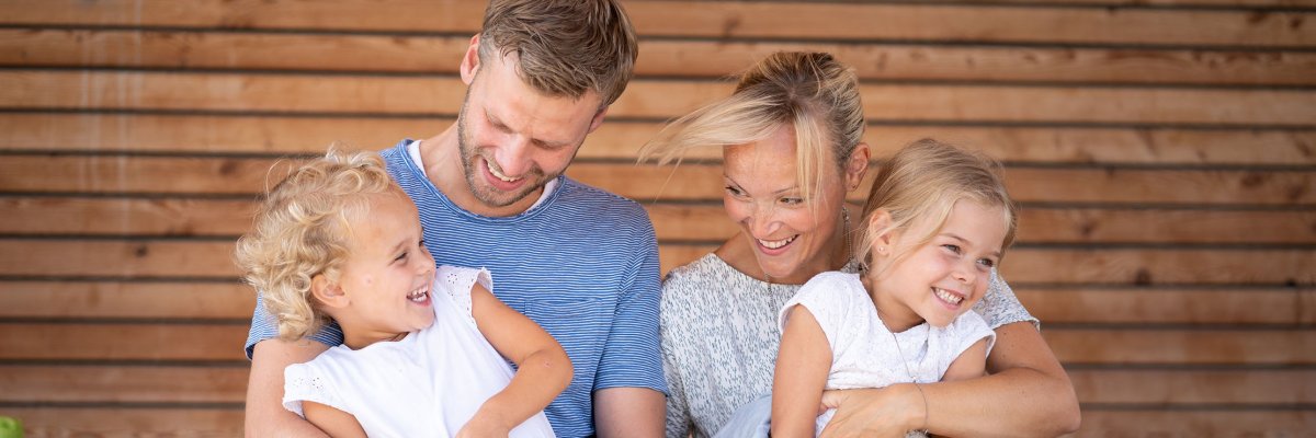 رجل وامرأة يضحكان مع فتاتين تجلسان على أحضانهما