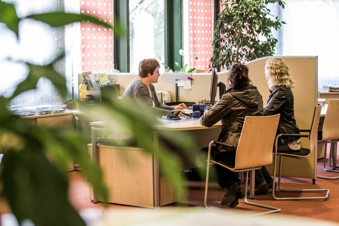 Служител в службата за регистрация разговаря с двама клиенти