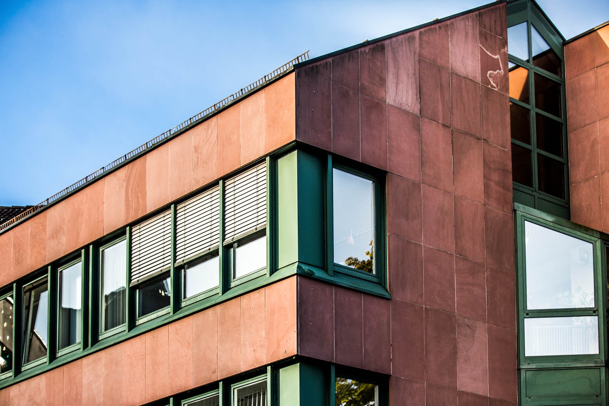 Детайлен изглед на червена сграда със зелени прозорци