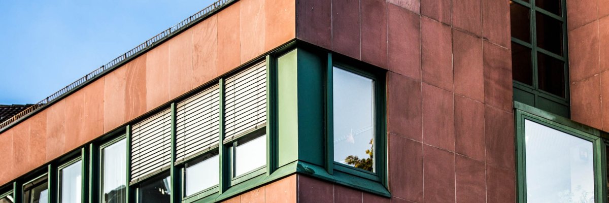 Детайлен изглед на червена сграда със зелени прозорци