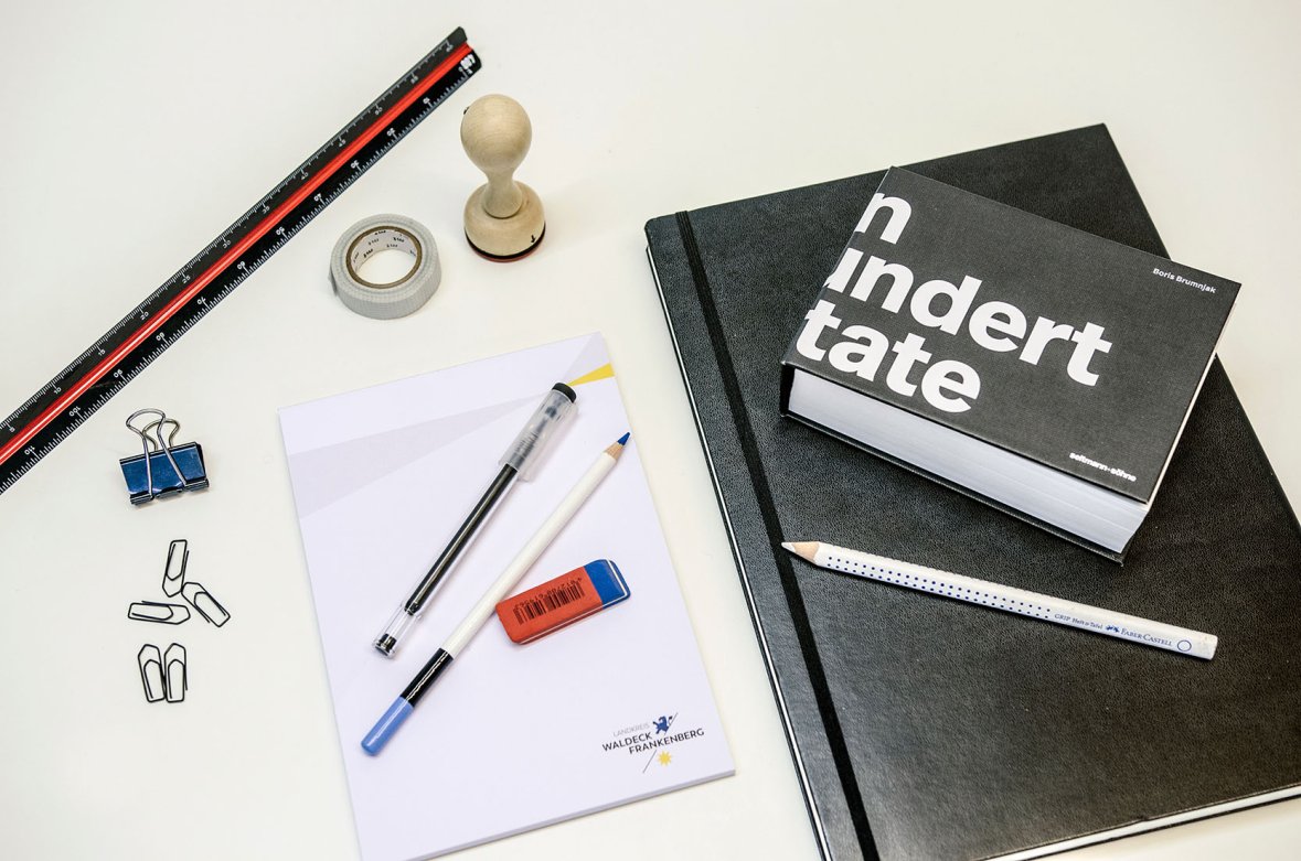 Many different office supplies lie on a table.