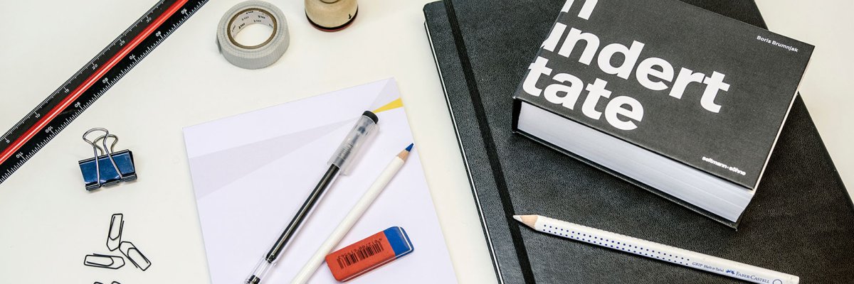 Many different office supplies lie on a table.