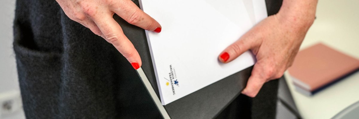 A woman holds a folder and a notepad.