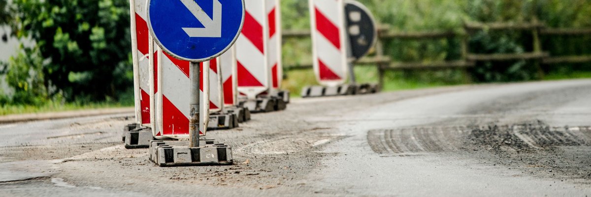 Barrier beacons and blue direction sign to the right at a road construction site