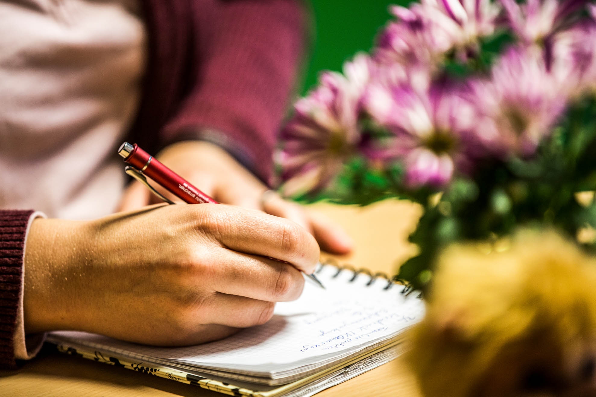One hand holds a pen to take notes on a pad