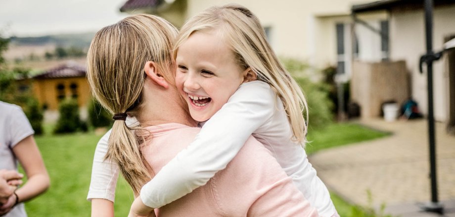 An older girl holds a younger girl in her arms