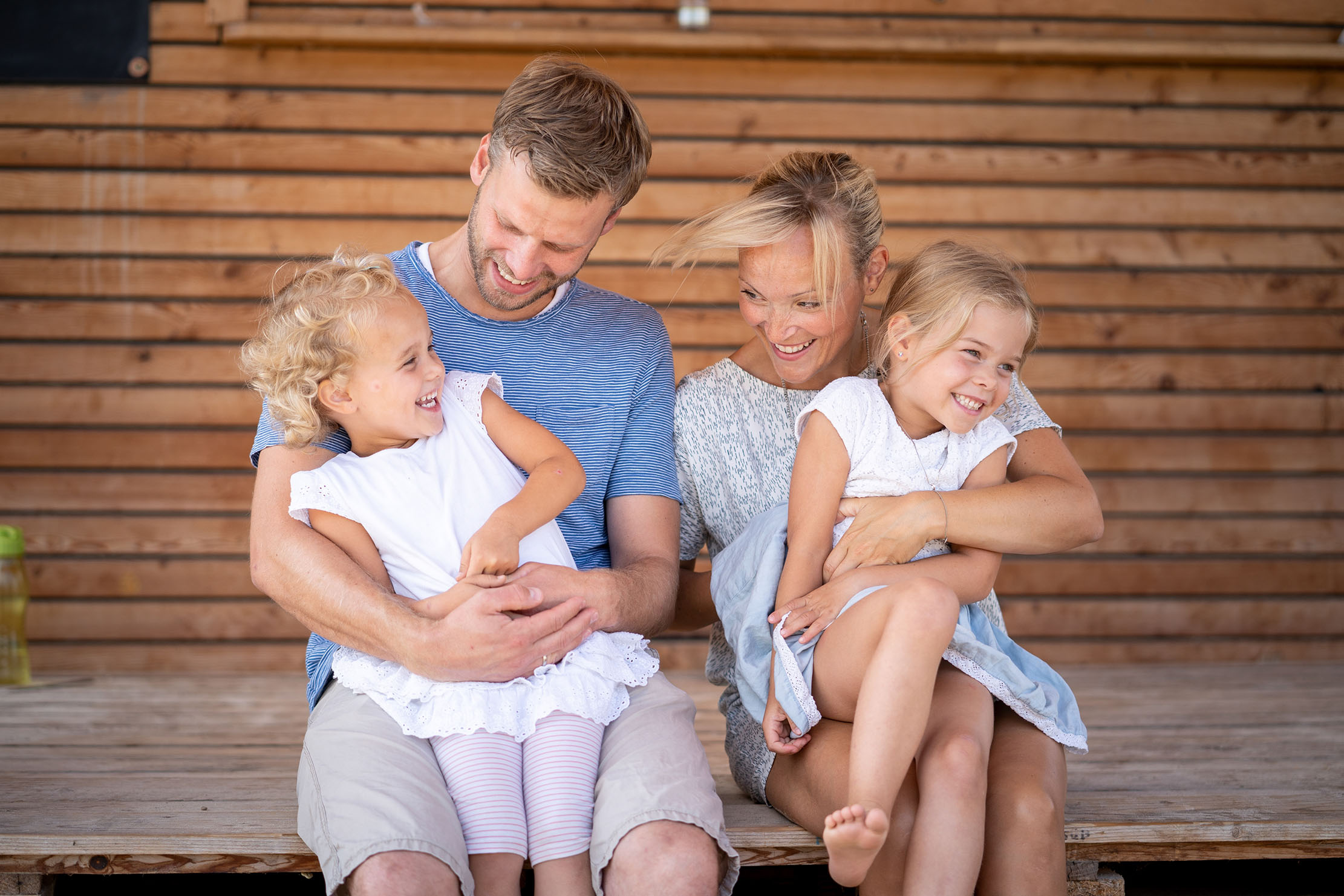 A man and a woman laughing with the two girls sitting on their laps