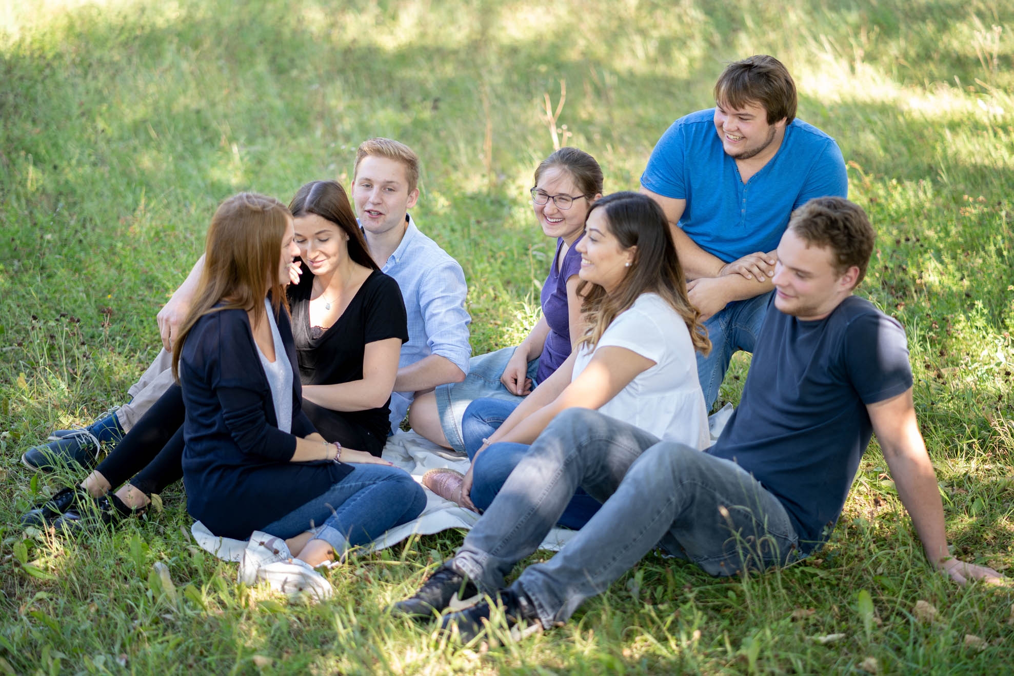 Seven teenagers sitting in the grass