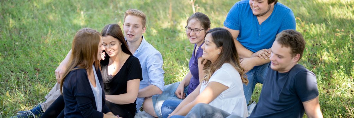 Seven teenagers sitting in the grass