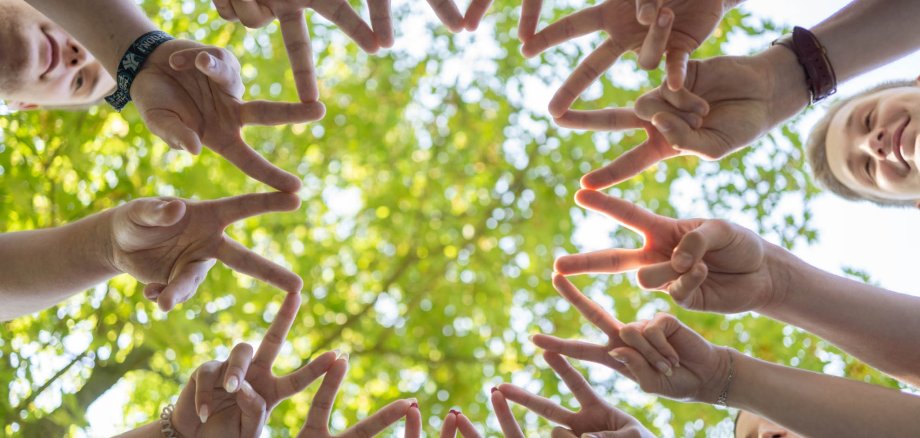 Young people form a star with two fingers spread apart.
