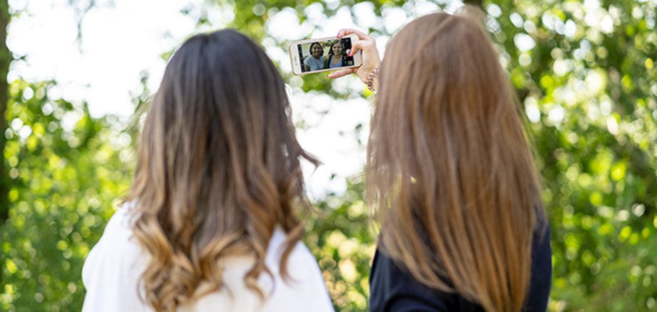 Back view of two female teenagers taking a selfie