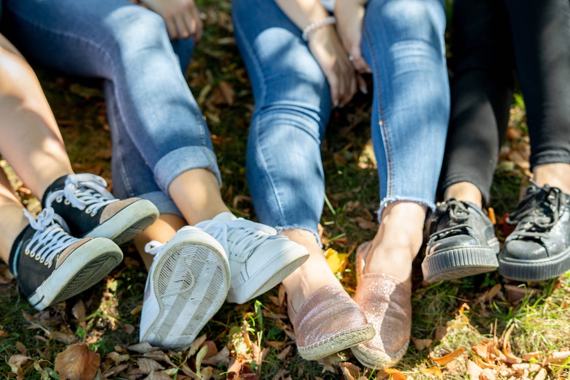Three pairs of legs sitting on the ground in the grass