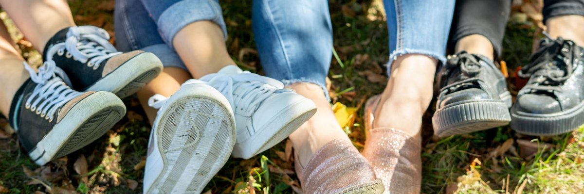 Three pairs of legs sitting on the ground in the grass