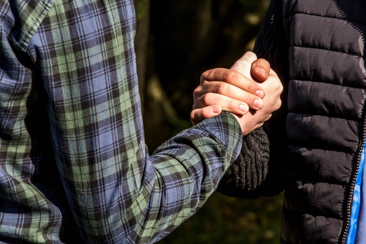 Two male youths greet each other with a fist handshake
