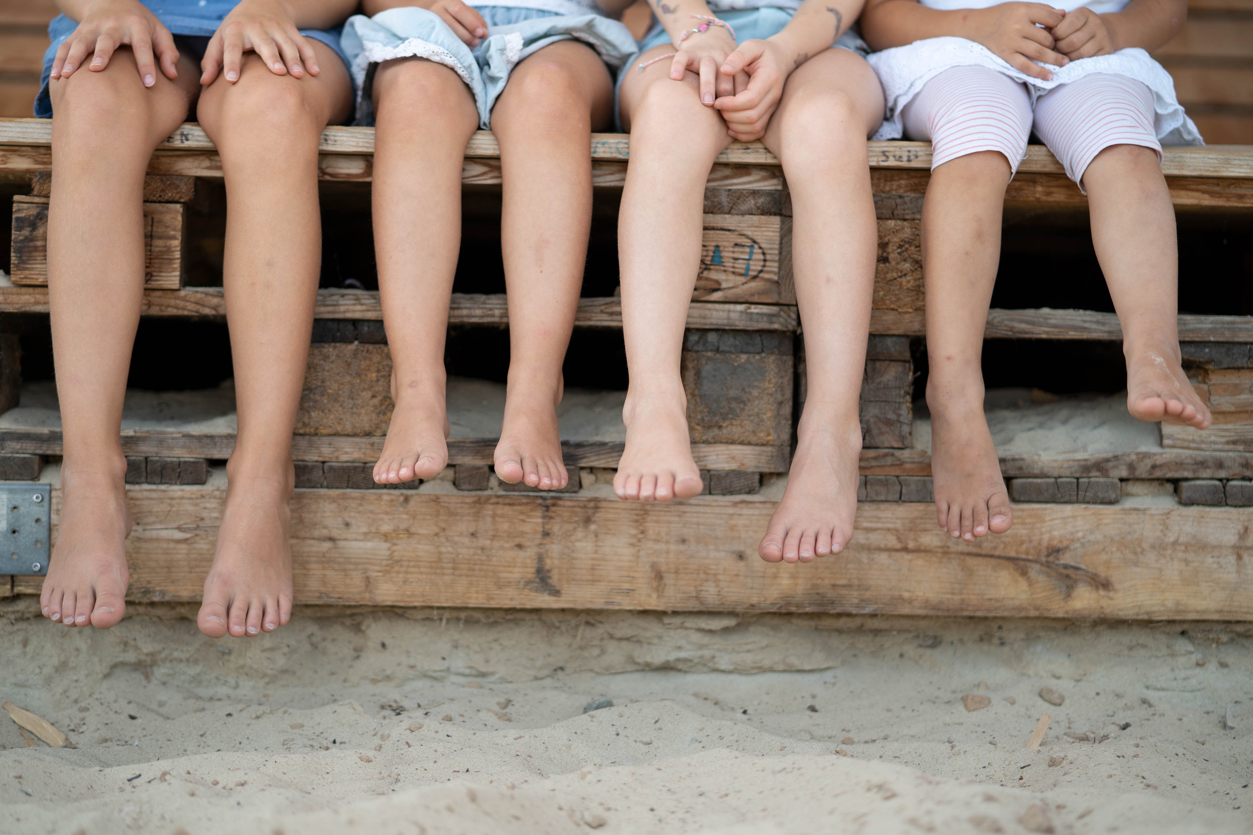 Legs Four pairs of legs with bare feet on a bench