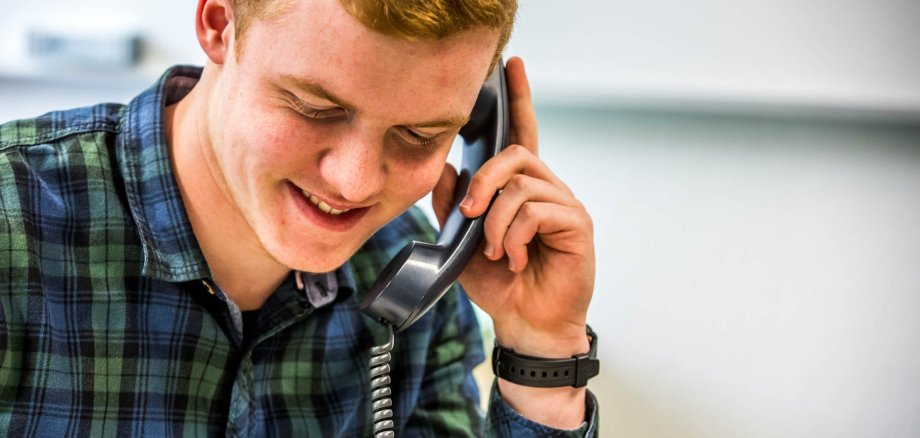 A smiling man is talking on the phone.