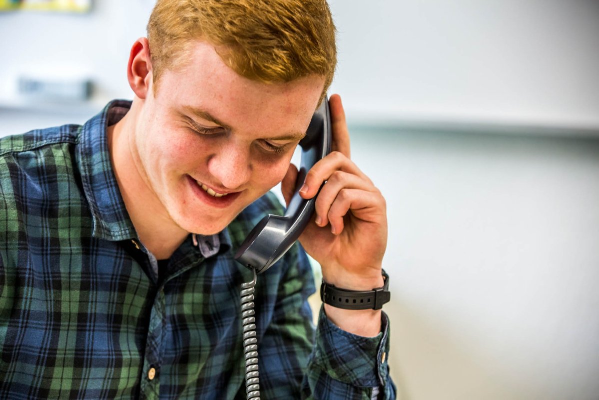 A smiling man is talking on the phone.