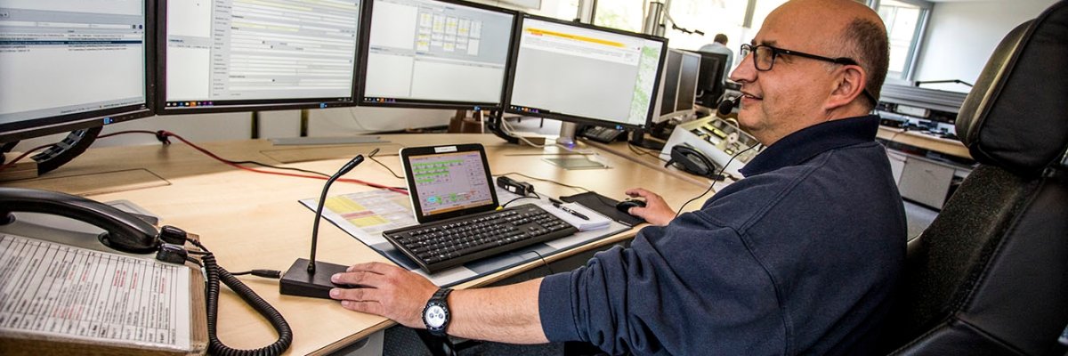 Man sitting in front of a computer with many screens