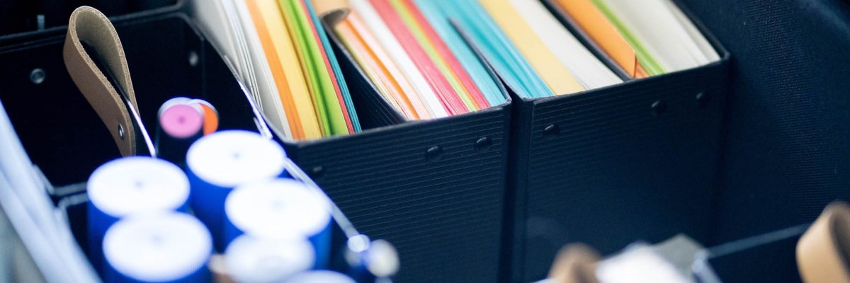 Colourful pieces of paper, thick pens and office supplies in a suitcase