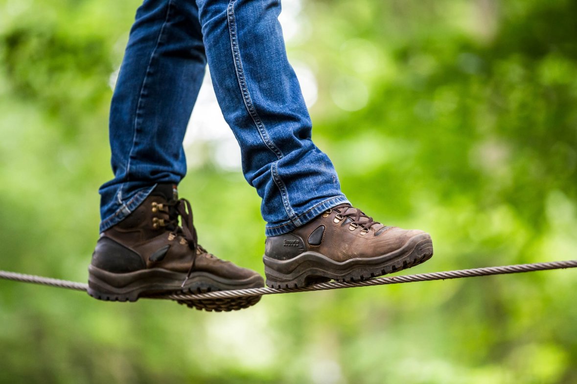 Man in hiking boots balancing over a rope
