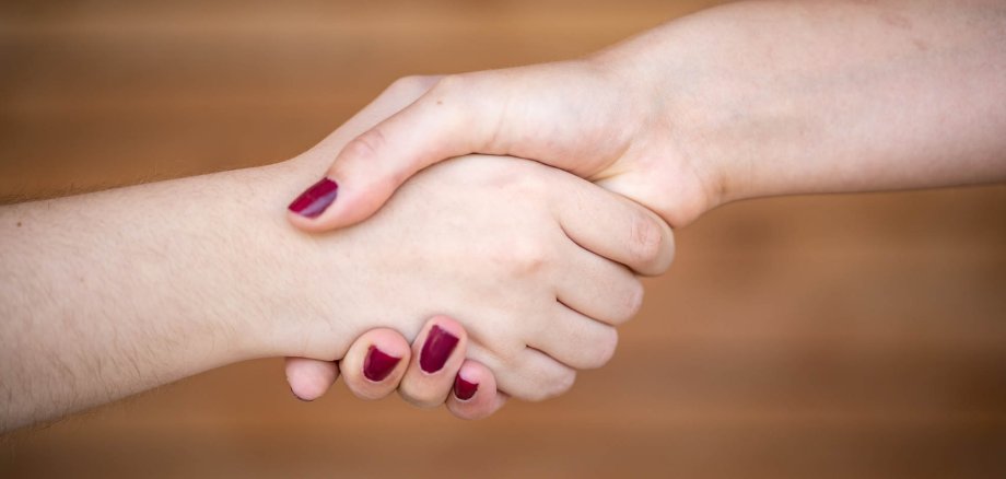Handshake of two female hands with red nail polish