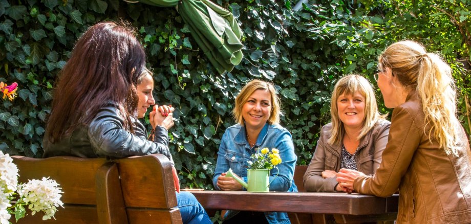 Group of young women sitting at wooden table outside