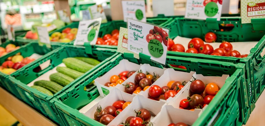 Vegetables in green plastic boxes lie in a shop