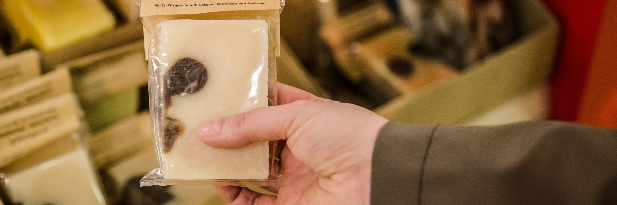 Hand holding homemade soap in a plastic wrapping