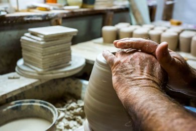Clay-covered hands form a clay jug