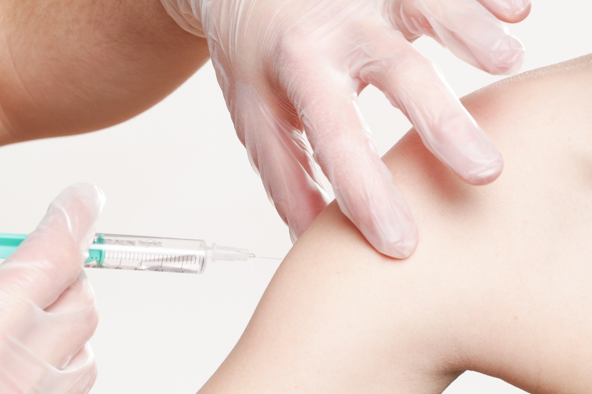 Syringe is applied to a left upper arm for vaccination