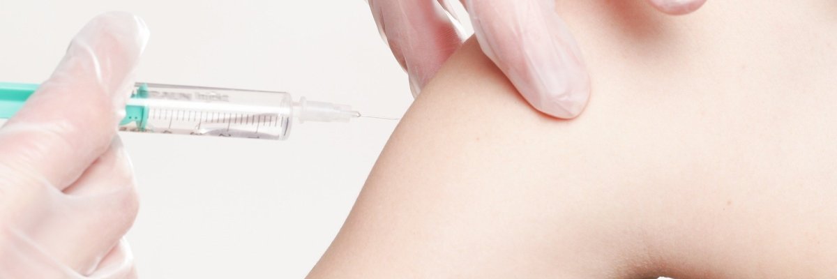 Syringe is applied to a left upper arm for vaccination