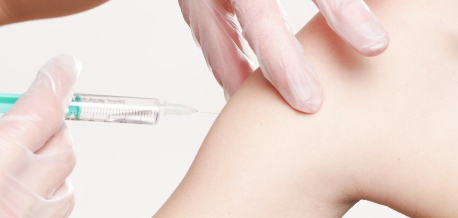 Syringe is applied to a left upper arm for vaccination