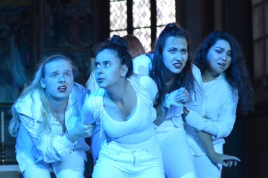 Theatre Week Korbach_pocomania Four youths dressed in white and illuminated in blue with distorted faces in a stooped posture.