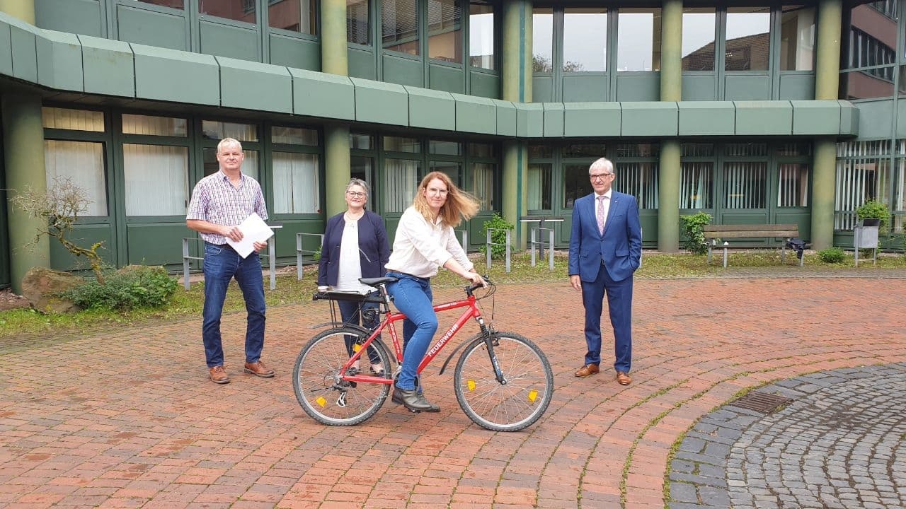 Adolf Scheuermann, Susanne Paulus, Nicole Sude and First District Councillor Karl-Friedrich Frese in front of the District House in Korbach. Ms Sude is sitting on a bicycle.
