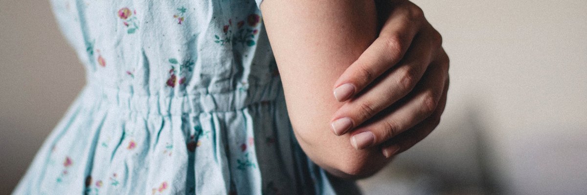 نما از سمت راست تنهٔ یک دختر، با پیراهن آبی روشن گل‌دار و دست‌های قلاب‌زده