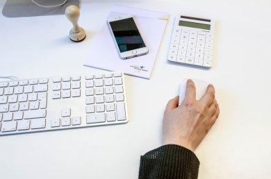 Bilgisayar iş istasyonu Birisi bir bilgisayar faresi kullanıyor. Yanında bir klavye ve diğer ofis malzemeleri var.