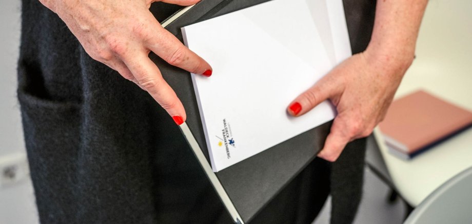 Bir kadın elinde bir dosya ve bir not defteri tutuyor.