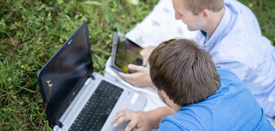 Dizüstü bilgisayarları ve akıllı telefonları olan iki genç