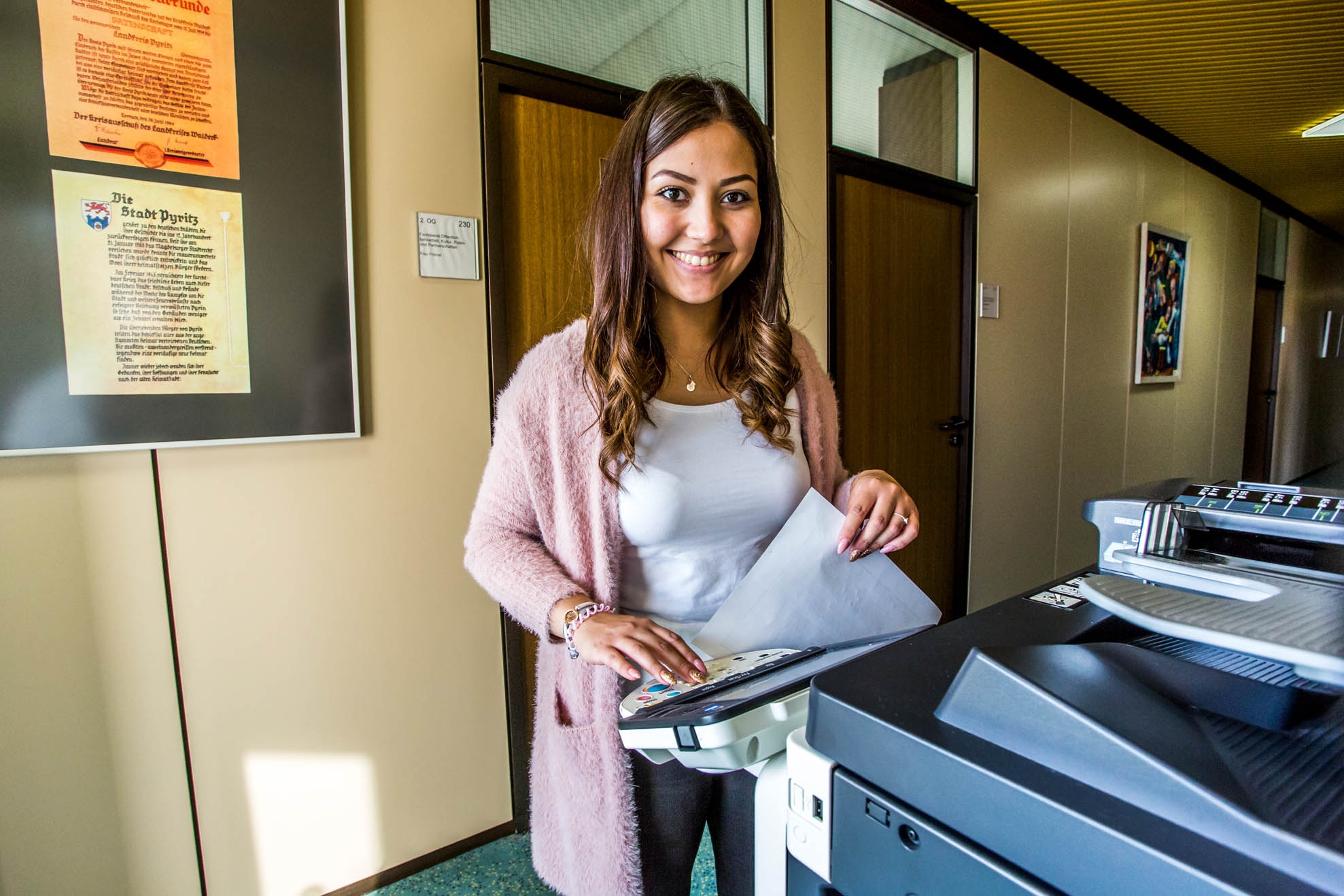 Усміхнена молода жінка біля ксерокса