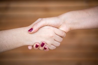 Люди Рукостискання двох жіночих рук з червоним лаком на нігтях