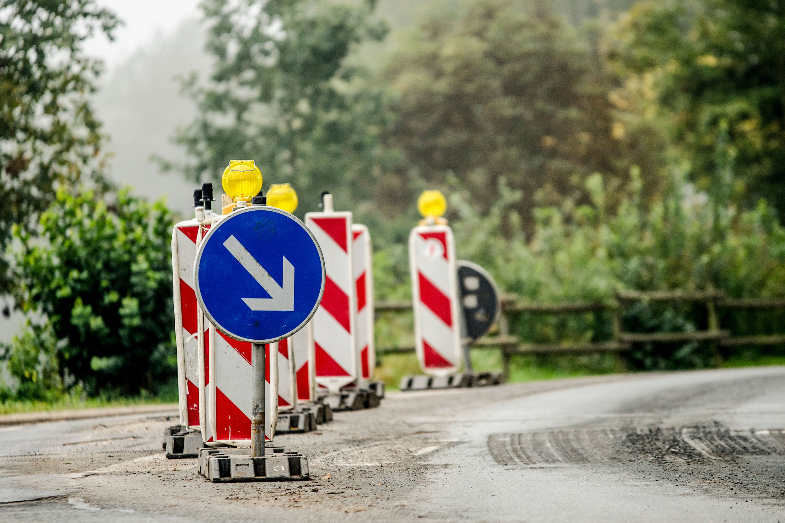 Bauschilder Absperrbaken und blaues Richtungsschild nach rechts an einer Straßenbaustelle