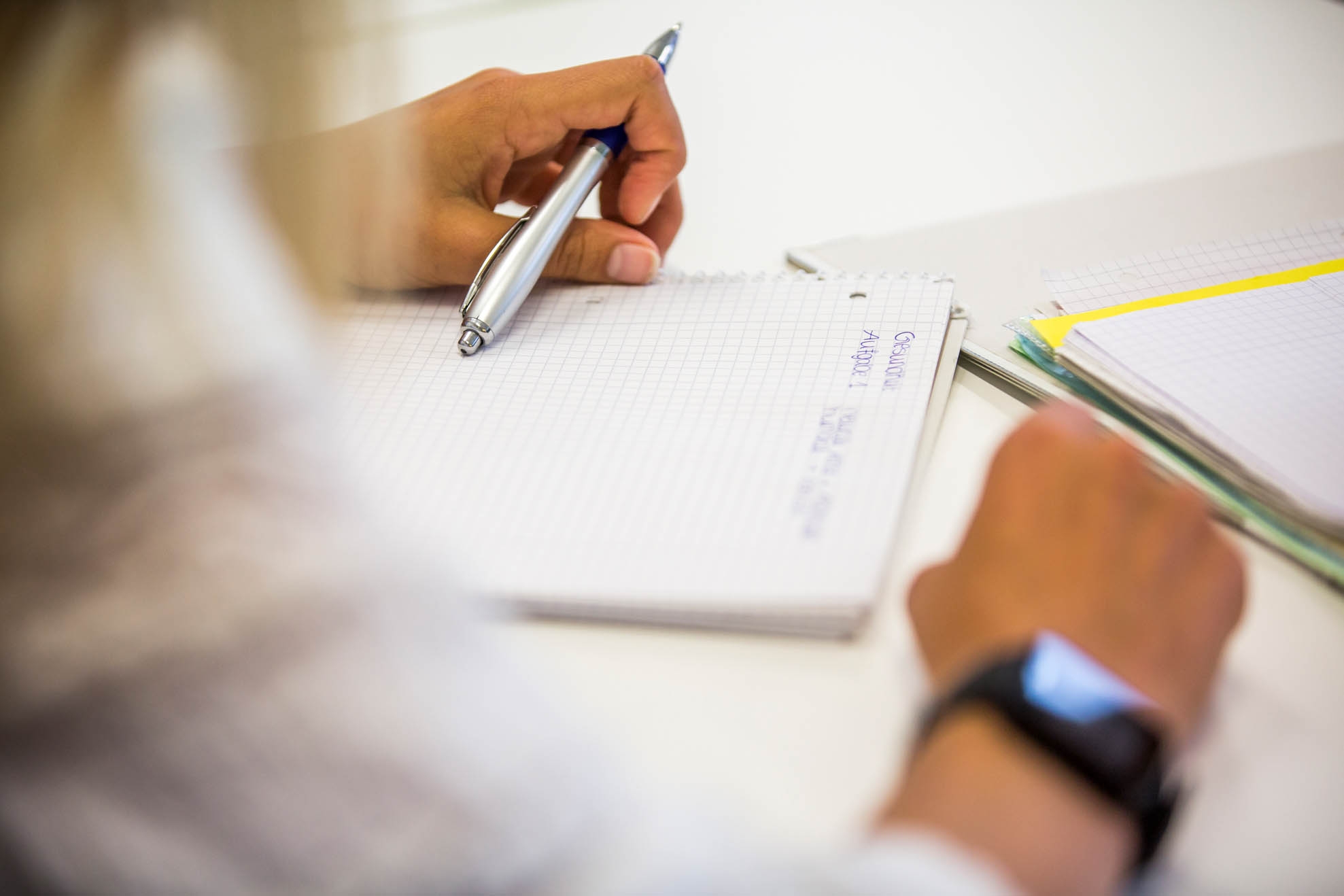 Eine Schülerin hält einen Stift und sitzt vor einem Block
