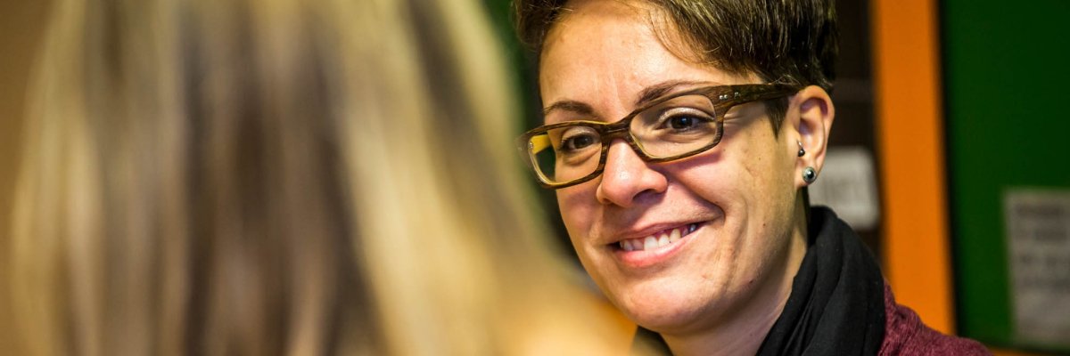 Eine Frau mit Brille unterhält sich lächelnd mit einer Schülerin
