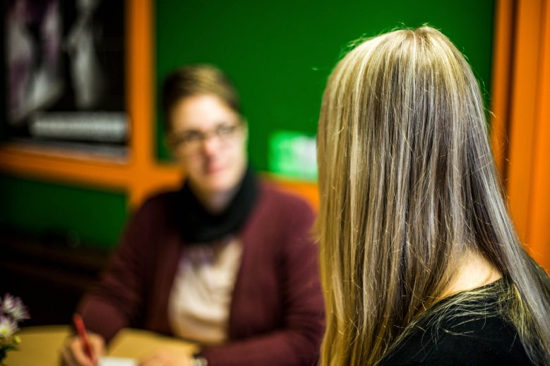 Rückenansicht einer Schülerin, verschwommen im Hintergrund eine Frau