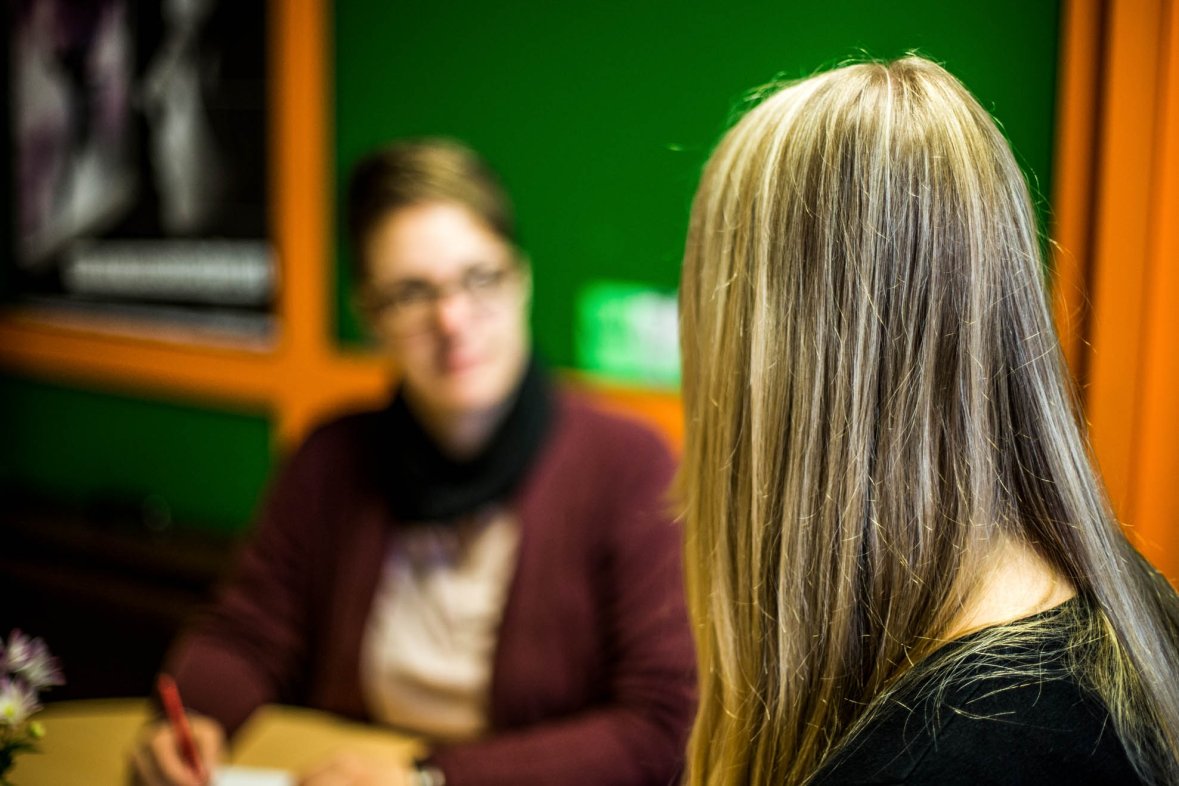 Rückenansicht einer Schülerin, verschwommen im Hintergrund eine Frau