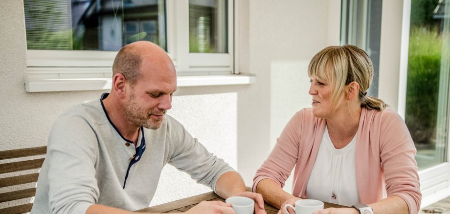 Ein Mann und eine Frau sitzen am Tisch und unterhalten sich