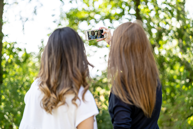 Rückenansicht von zwei weiblichen Jugendlichen die ein Selfie machen