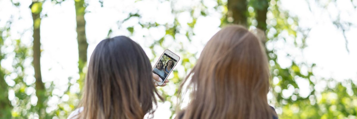 Rückenansicht von zwei weiblichen Jugendlichen die ein Selfie machen