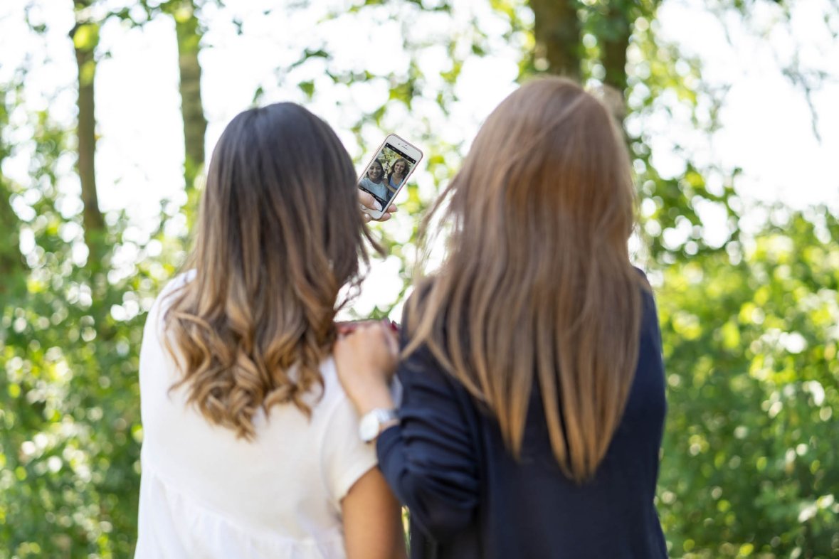 Rückenansicht von zwei weiblichen Jugendlichen die ein Selfie machen