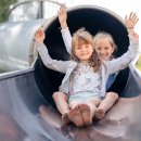 Zwei Mädchen kommen aus einem Rutschtunnel gerutscht